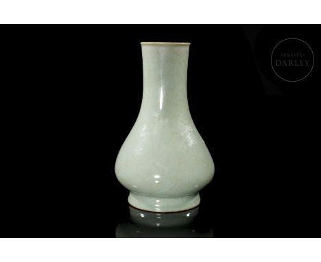 A ceramic vase with a stylised cylindrical neck ending in a bulging, pear-shaped belly. It is decorated with a thick celadon 