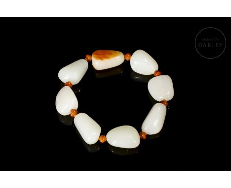 Carved white jade, with reddish and amber flecks. The bracelet is composed of a total of eight slightly triangular shaped bea