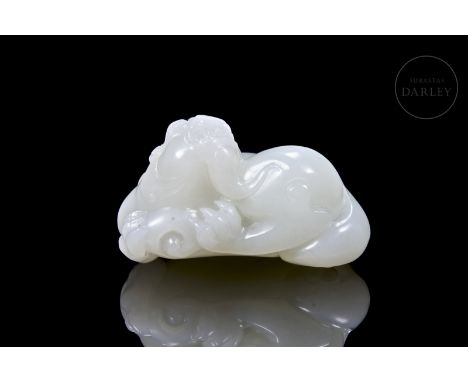 Elegantly carved white jade with an amber-reddish tinge. It depicts a beast with a sinuous and robust body, holding a spiral 