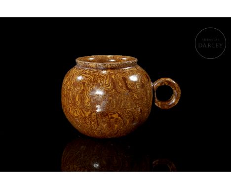 Ceramic modelled in the form of a jug, with a circular body flanked by a curved handle and ending in a small rounded mouth. I