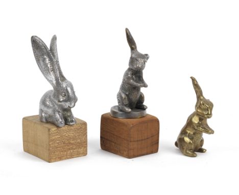 Three Rabbit mascots,comprising a nickel plated brass mascot by Desmo, British, late 1920s, 12cm high on a wooden block base,