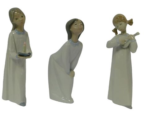 Three Lladro porcelain figures, each wearing a night gown, one holding a chamber stick, 22cm high, another a musical instrume