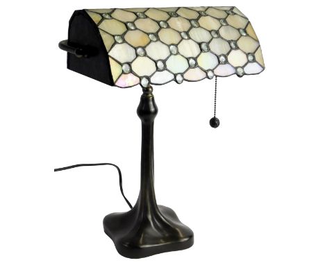 A 20thC Tiffany style desk lamp, the shade with cream lustre glass panels interspersed by roundels, on a tapering column, on 