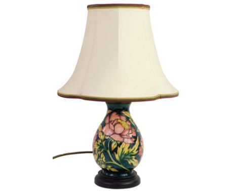 A Moorcroft pottery vase decorated in the Peony pattern, designed by Philip Gibson, dark green ground, on a hardwood base, wi