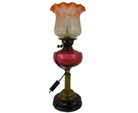 A Victorian oil lamp, with an etched clear glass shade decorated with flowers with a pink waved rim, the lamp with a ruby gla