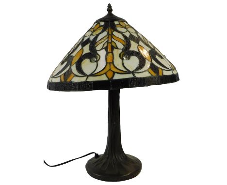 A Tiffany style table lamp, the tapering shade decorated with scrolling and leaf motifs in cream, brown and orange, on a tape