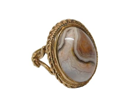A 9ct gold and agate ring, the central cabochon agate in a double rope surround, on open out splayed shoulders, size J, 6.9g 