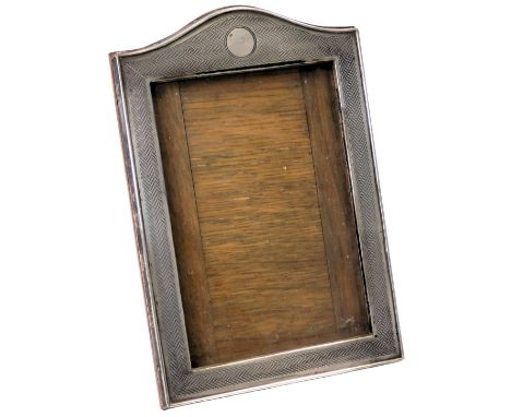 A George V silver photograph frame, with a shaped top above a central roundel, engine turned decoration, on a strut back, Bir