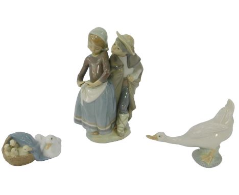 A Lladro porcelain figure group, modelled as a boy wearing a cloak, beside a girl, 21cm high, together with a Lladro goose, 1