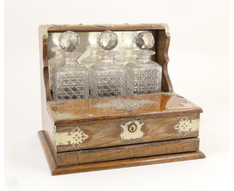 Late Victorian oak tantalus, circa 1890, having silver plated mounts with an inscribed presentation cartouche, supporting thr