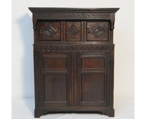 Welsh oak joined Cwpwrdd Deuddarn, late 17th Century, having a lunette carved frieze over two lozenge carved cupboard doors f