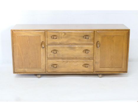 Ercol light elm sideboard, fitted with a central configuration of three drawers, flanked on either side with two cupboard doo