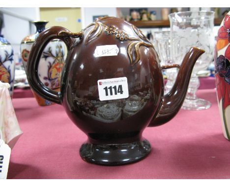 A Brameld Cadogan Teapot, the treacle glazed ovoid body applied with sprigs of flowers, unmarked, 19cm high.