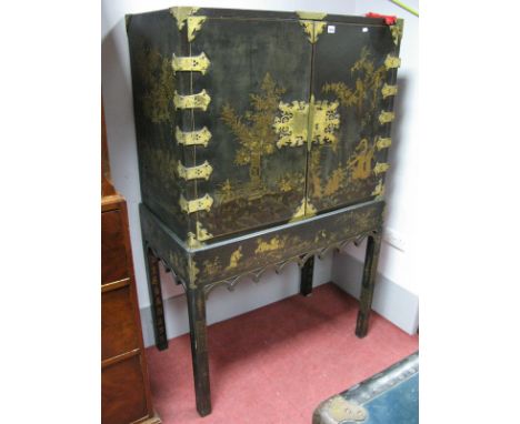 An XVIII Century Chinese Black Lacquer Cabinet on Stand, the doors decorated with figures and a vase of flowers, gilded lock 