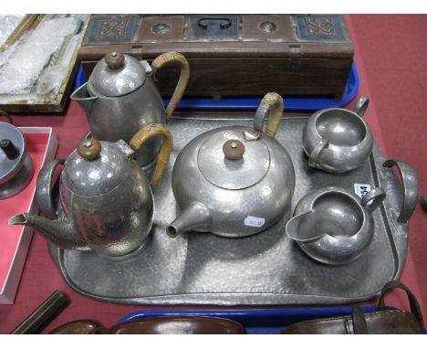 A Tudric Beaten Pewter Five Piece Tea Service, with wicker handles, and a matching two-handled shaped rectangular tray, impre