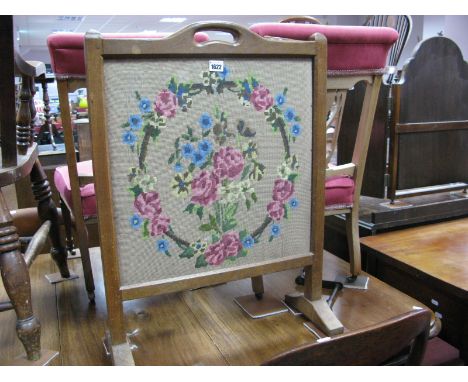 An Oak 'Lizardman' Fire Screen, standard supports with central carrying handle and lizard to the top rail, embroidered gros p