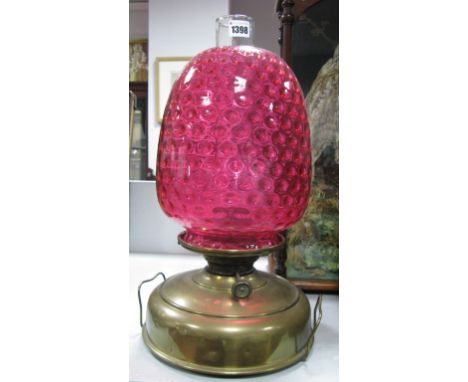 An Early XX Century Brass Oil Lamp, of two handled circular form, with dimpled cranberry glass shade, 48cm high.