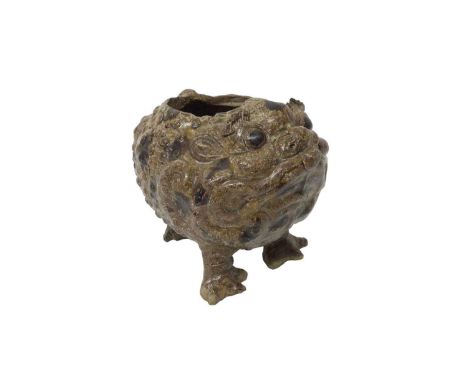 A grotesque three-legged pottery toad, covered with warts, glazed in tones of brown, in the style of Burmantofts, 15cm high.
