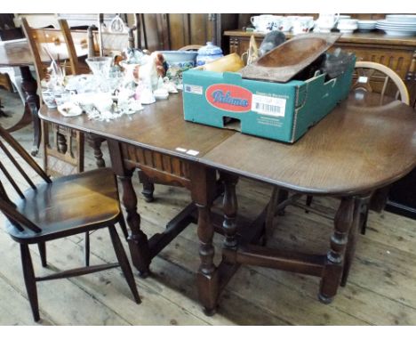 An oak gate legged dining table on turned legs together with four Fleur De Lys backed Windsor dining chairs