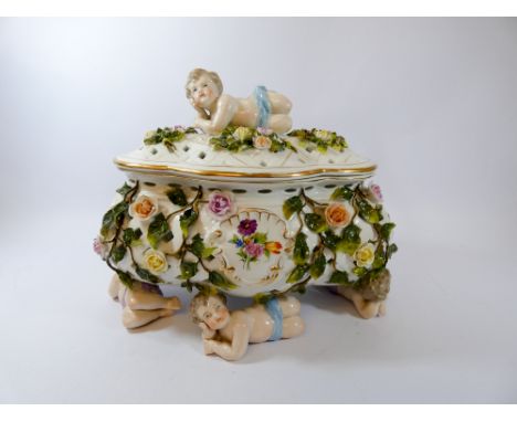 A German floral encrusted pierced trinket box and cover supported by cherubs, 25cm across, blue cross sword mark to base 
