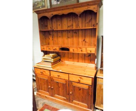 A pine kitchen dresser with shelf back and spice drawers standing on a three drawer and cupboard base 