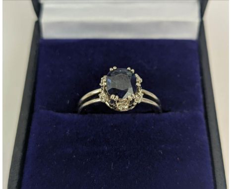 A SAPPHIRE AND DIAMOND SET DRESS RING, the single stone sapphire of approximately 1 carat, claw set and a gallery edge set wi