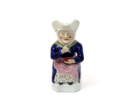 A rare female Snuff Taker Toby jug, c.1830, wearing a blue dress with a pink apron, holding a circular snuff box and raising 