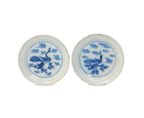 A pair of delftware plates or shallow bowls, c.1720, possibly London, each painted in blue with a simplistic peacock perched 