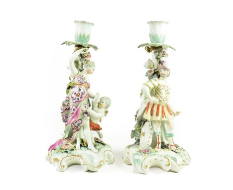 A Pair of Derby Porcelain Figural Candelabra, circa 1765, modelled as Mars and Venus, he with his various trophies, she with 