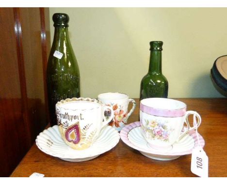 Two green glass bottles, two Southport Commemorative cups and saucers and cup