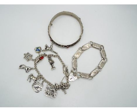 A charm bracelet with eleven continental charms, variously stamped 800, 835 etc, a white metal bracelet with chased decoratio