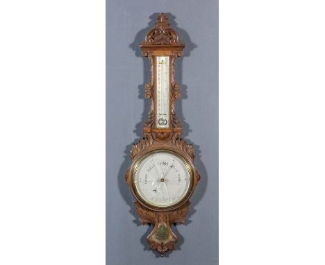 An Oak Wheel Cased Barometer and Thermometer, Edwardian, the 7.5ins silver dial and mercury thermometer contained in leaf car