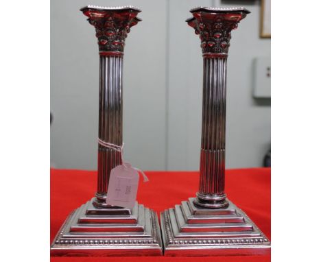 A pair of silver candlesticks, Corinthian column design, on square stepped bases, having removable beaded drip pans, Sheffiel
