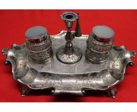 A silver plate standish, with a pair of cut glass inkwells either side of a central taper holder with removable snuffer, base