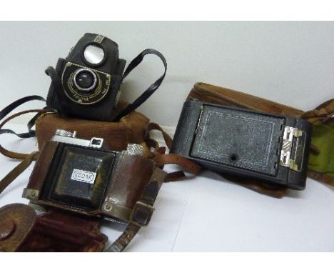 Three cameras comprising a folding camera, Kodak and Ensign