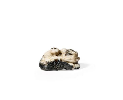 A CHINESE CREAM JADE MODEL OF A BUDDHIST LION DOG, 17TH CENTURY In a recumbent position, its head turned to the right and wit