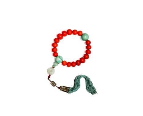 A CHINESE CORAL AND JADEITE ROSARY BRACELET, QING DYNASTY The graduated coral beads divided by two circular jadeite beads, on