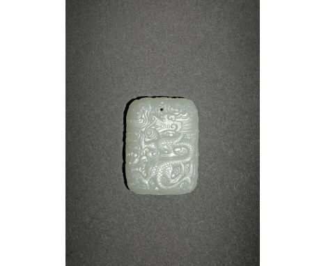 A CHINESE PALE CELADON JADE DRAGON PLAQUE, 20TH CENTURY Carved in relief to each side with a writhing dragon amongst cloud sc