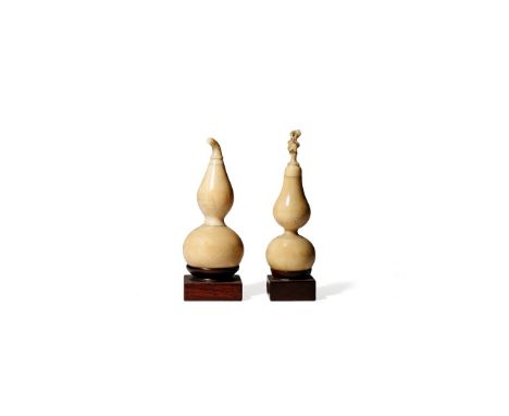 † TWO CHINESE IVORY MINIATURE MODELS OF GOURDS, 19TH CENTURY Each carved with a stalk forming the finial, raised on hardwood 