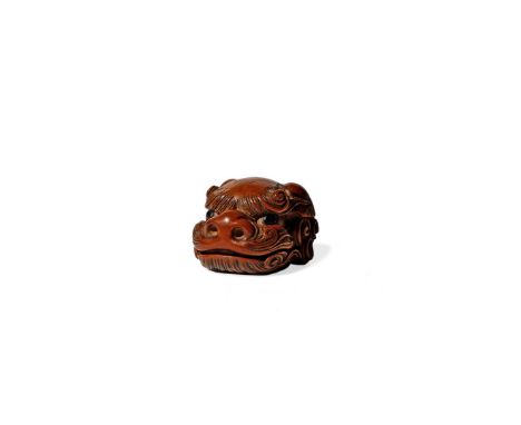 A JAPANESE WOOD NETSUKE, 19TH CENTURY Carved as a shishi mask, the articulated jaw opening to reveal a large tongue and point