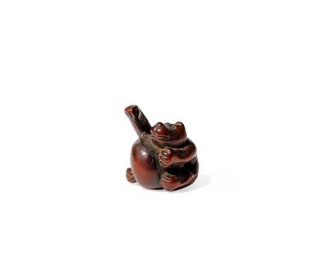 A JAPANESE WOOD NETSUKE, 18TH/19TH CENTURY Carved as a pot-bellied tanuki seated in the pose of a manuki neko with one arm ra