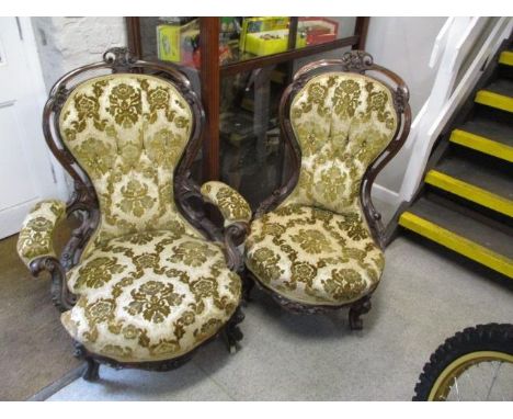 A Victorian mahogany and upholstered His and Her's open armchairs, ornately carved on French cabriole legs and ceramic castor