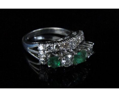 A white gold diamond and emerald ring, the centre raised row with a centre square cut emeral flanked by brilliant cut diamond