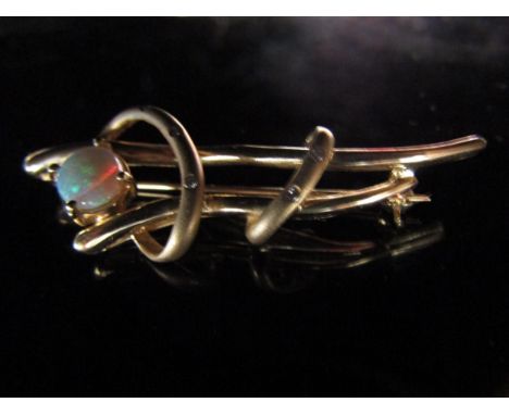 A gold brooch with an oval opal in free form setting studded with diamonds, stamped 585, 6.6g with original receipt 