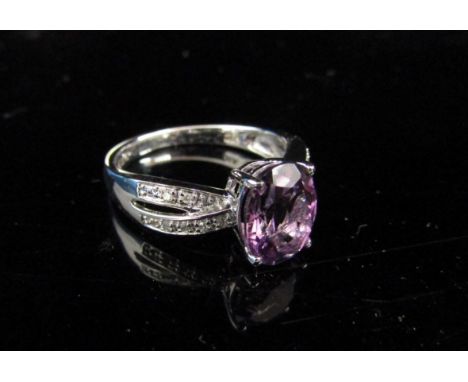 A white gold ring with oval amethyst flanked by two rows of diamond chips, stamped 375. Size M, 2.7g 