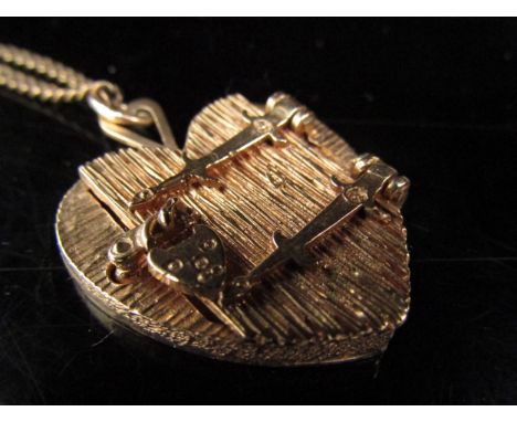 A 9ct gold heart shaped locket with textured bark effect, the front with an opening hinged door with heart shaped lock, hung 