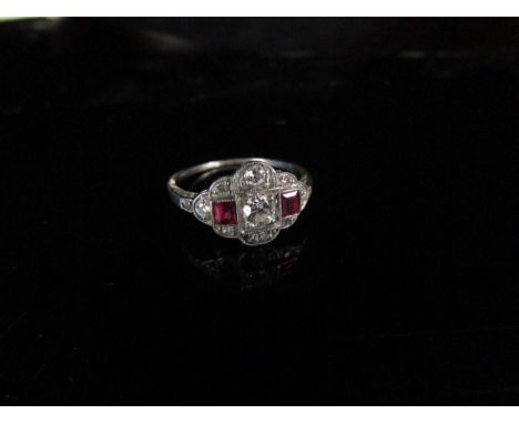 An Edwardian ruby and diamond ring, the central diamond 0.20ct approx flanked by square cut rubies all framed by old cut diam