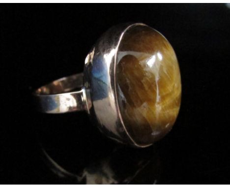 A gold ring set with a large cabochon tigers eye. Size O, 6.8g 