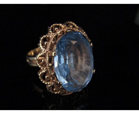 A 9ct gold ring with a large oval blue stone in high open basket mount. Size Q/R, 12.5g 