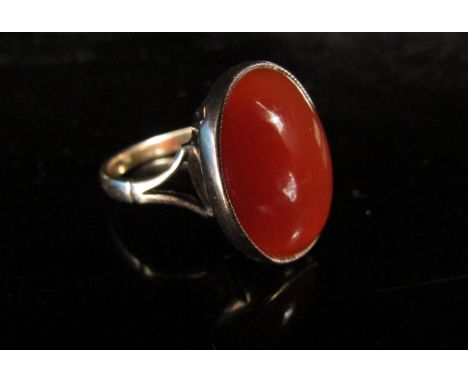 An unmarked gold ring with a cornelian oval stone in rubover setting. Size O, 4.8g 